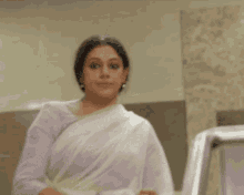 a woman with her arms crossed is wearing a white saree