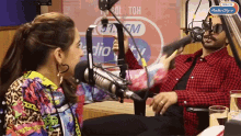 a man and a woman are sitting in front of a microphone in front of a sign that says radio city