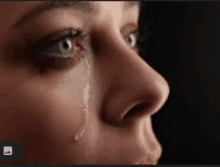 a close up of a woman 's face with a tear running down her face .