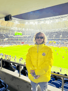 a person in a yellow moncler jacket stands in a stadium