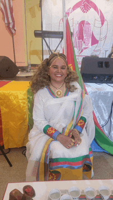 a woman in a white dress sits in front of a sign that says ' ethiopian ' on it