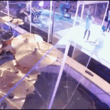 an aerial view of a drum set on a stage with people standing in the background .