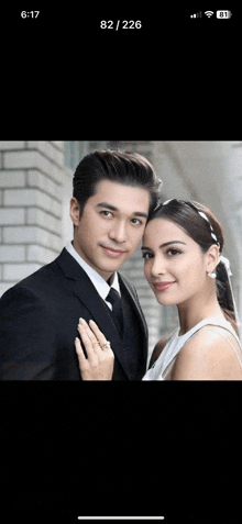 a man in a suit and tie and a woman in a white dress are posing for a picture together .