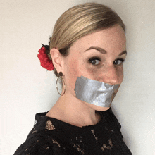 a woman with a flower in her hair has duct tape on her mouth