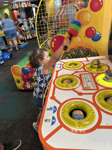 a little girl is playing a game with a sign that says " smash "