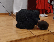 a man is kneeling down on a wooden floor with a cord hanging from his neck