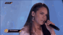 a woman is singing into a microphone while wearing earrings .