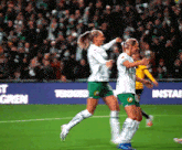 two female soccer players are celebrating a goal in front of a banner that says ' install ' on it