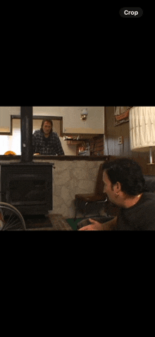 a man sitting in front of a fireplace with a crop button on the bottom