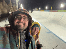 a man and a woman are posing for a picture in front of a snowboard ramp that says allianz