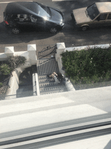 a woman sits on a set of stairs in front of a car parked on the side of the road