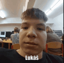 a young man is taking a selfie in front of a group of people in a classroom .