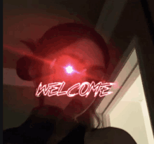 a woman 's face is lit up with the word welcome in red letters