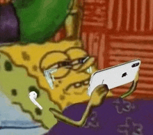 spongebob squarepants is sitting on a bed using a cell phone and headphones .