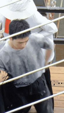 a man in a gray shirt is standing in a boxing ring .