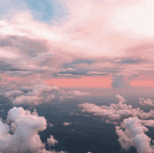 an aerial view of a cloudy sky with a pink sunset in the background