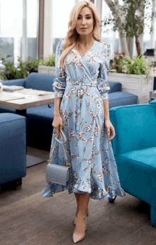 a woman wearing a light blue floral dress is standing in a restaurant