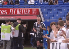 a group of soccer players are standing on a field in front of a sign that says `` fly better '' .