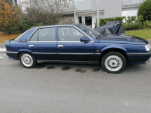 a blue car is parked on the side of the road in front of a building with a black cover on it