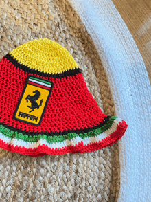 a red yellow and green crocheted hat with a ferrari logo on it