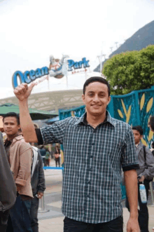 a man in a plaid shirt stands in front of the ocean park entrance