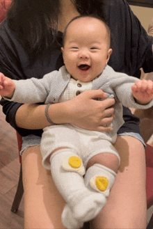 a woman is holding a baby who is wearing a pair of socks with eggs on them