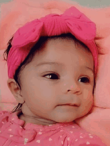 a baby girl wearing a pink headband and a pink dress