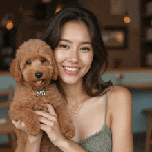 a woman is holding a small brown dog with a collar that says mb on it