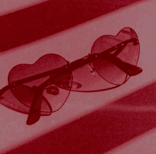 a pair of red heart shaped sunglasses on a red surface