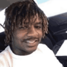 a man with dreadlocks is sitting in the back seat of a car smiling .