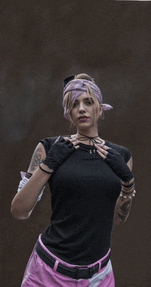 a woman wearing a black shirt and pink pants has a tattoo on her arm