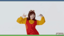 a woman in a red vest and yellow shirt is dancing and wearing sunglasses .