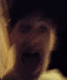 a close up of a person 's face with their mouth open in a dark room .