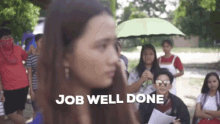 a woman is standing in front of a group of people holding an umbrella and a sign that says job well done