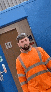 a man in an orange shirt stands in front of a blue door with a sign that says toilets on it