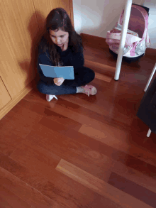 a girl sitting on the floor reading a book