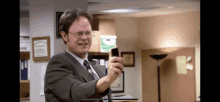 a man in a suit and tie holds a cell phone