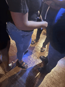 a group of people are standing on a wooden floor with one wearing a black shirt with the letter e on it