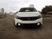 a white fiat car is parked on a concrete surface