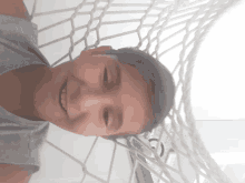 a young boy laying in a hammock smiling