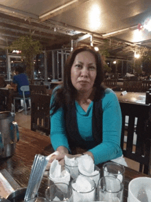 a woman in a blue shirt is sitting at a table