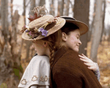 a woman in a straw hat is hugging another woman in a brown sweater