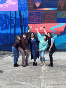 a group of women are posing in front of a mural that says ' a ' on it