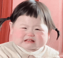 a little girl with pigtails is crying and making a funny face .