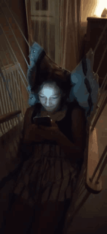 a woman laying in a hammock looking at her cell phone