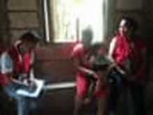 a blurry picture of a group of people sitting in front of a window in a room .