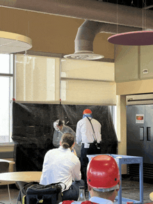 a man wearing a red hard hat stands in front of a table that says reception