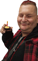 a man in a plaid shirt holds a small cake with a candle in it