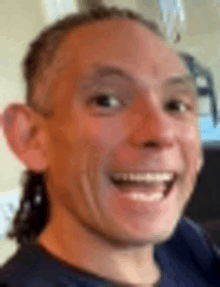 a close up of a man 's face with a ponytail smiling .