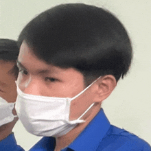 a man wearing a blue shirt is wearing a white mask